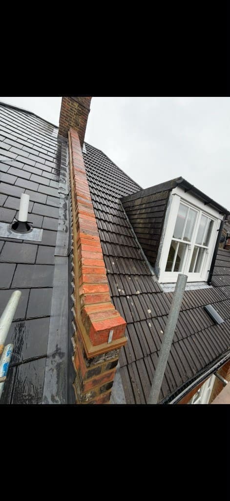 New parapet wall brickwork with coping stones between tiled roof sections